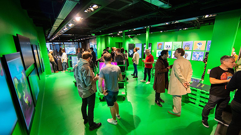 Guests exploring a green-lit exhibition space at a Creator Nations event.